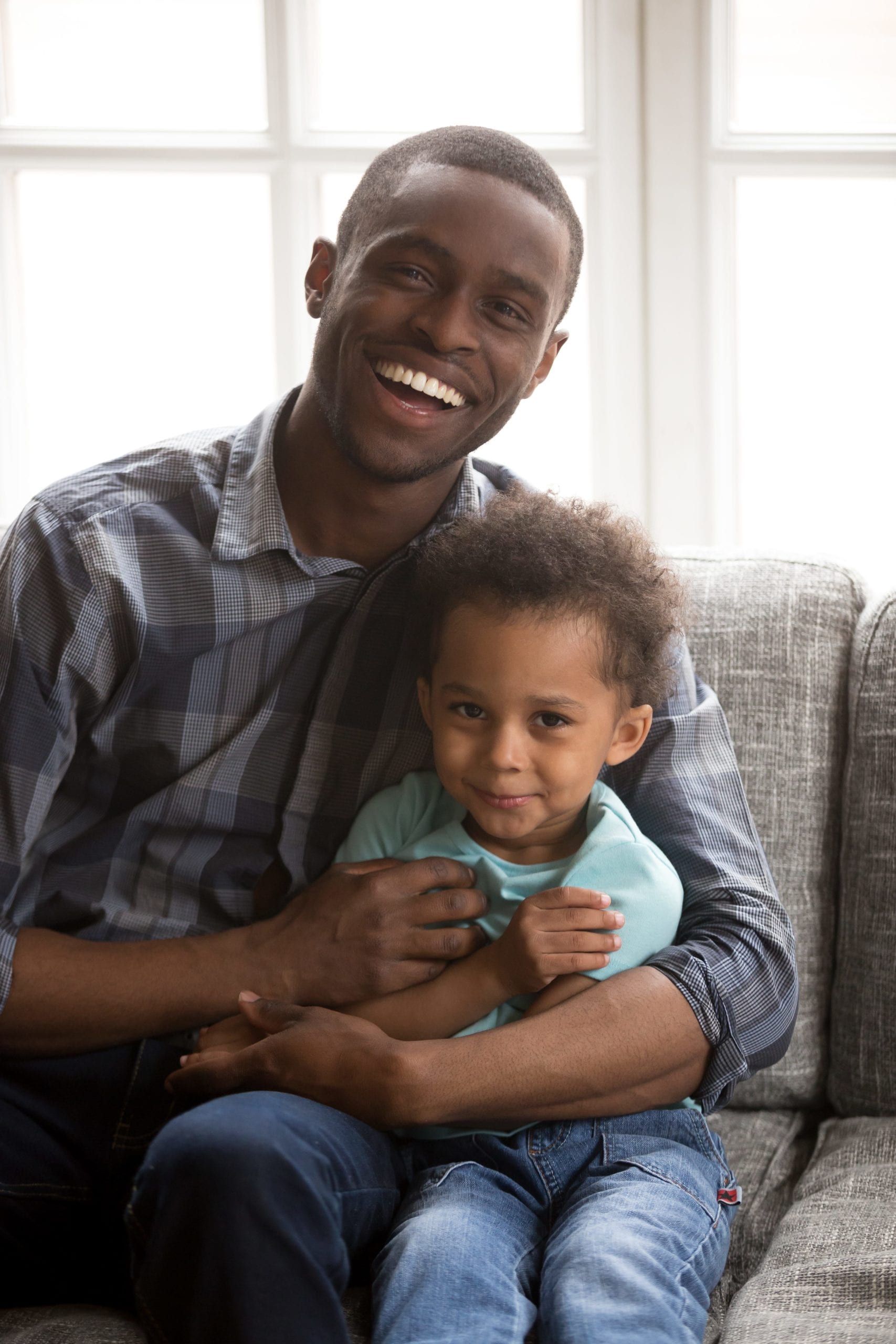 Loving father with little son sitting looking at camera indoors